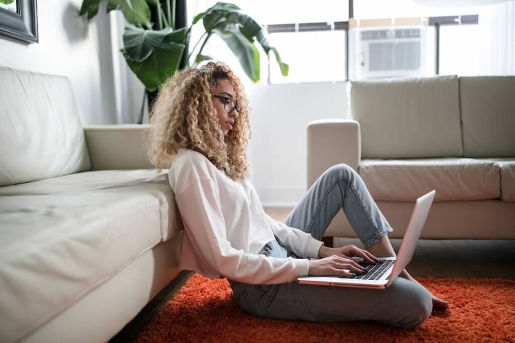 Woman sitting comfortably at home blogging on her laptop