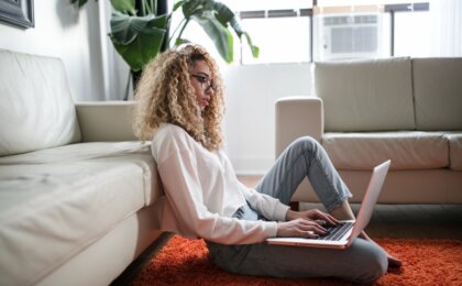 Woman sitting comfortably at home blogging on her laptop