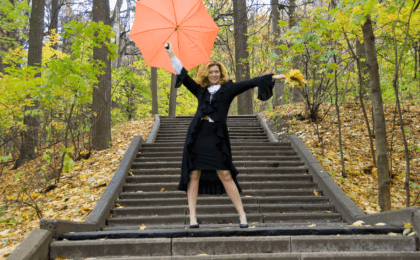 woman standing on steps with arms open wide, feeling fabulous after 50.